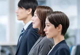 前方を見つめる3人のビジネスパーソン（男性、女性、女性）のプロフィール。チームワークや協調性を表現